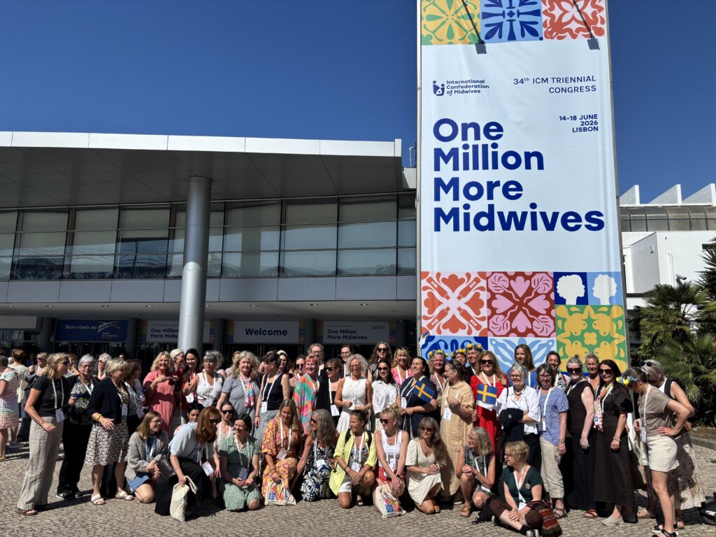 Gruppbild på svenska barnmorskor på plats utanför kongresslokalen i Lissabon. Med en stor banner bakom där det står One Million more Midwives.